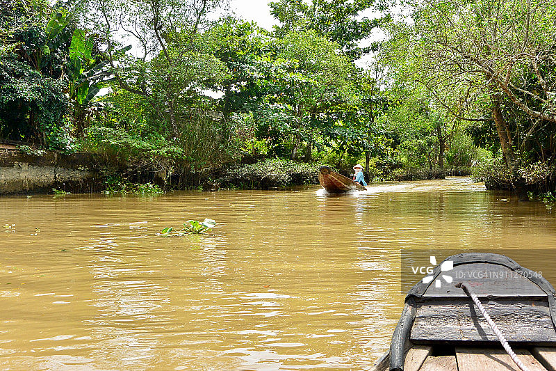 越南湄公河三角洲运河上的一艘摩托艇正驶近一艘木制划艇图片素材