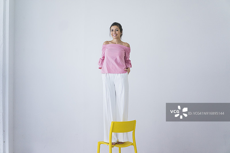 一个笑着站在黄色椅子上的女人的肖像图片素材