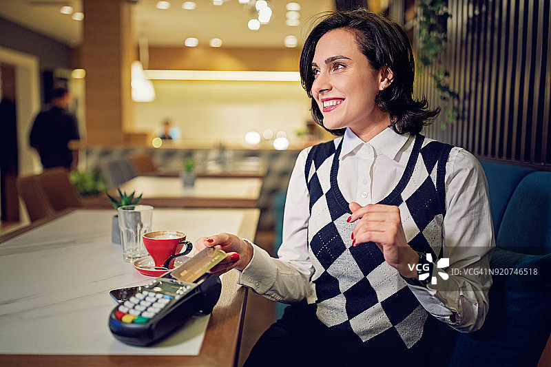 一名女子在餐厅用非接触式信用卡付款图片素材