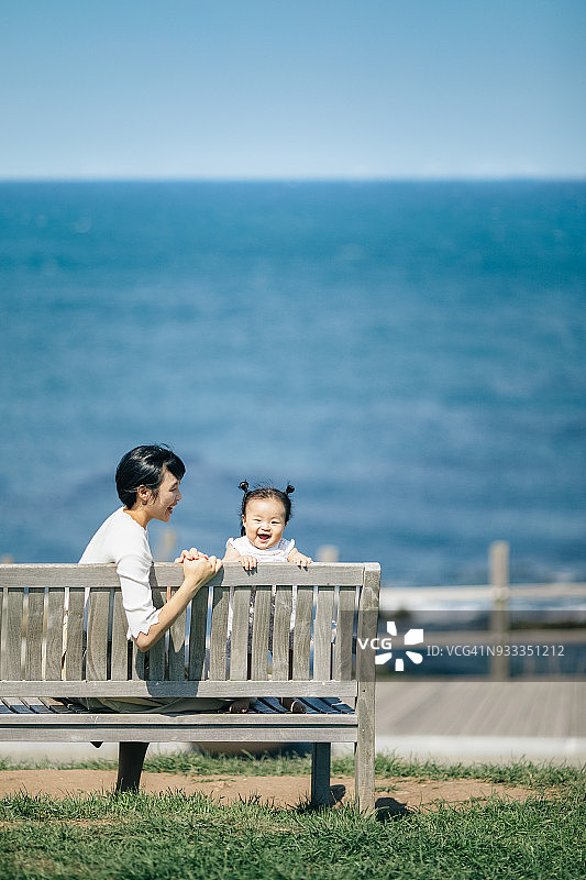 一个孩子坐在长凳上的快乐妈妈图片素材