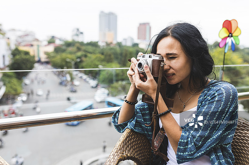 越南，河内，一名年轻女子正在用老式相机拍照图片素材