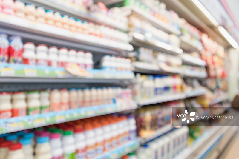 抽象模糊超市杂货店的冰箱货架上的新鲜牛奶瓶和乳制品图片素材