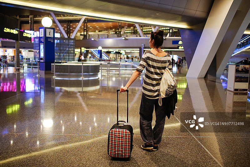 带着行李箱独自在卡塔尔机场旅行的年轻女子图片素材