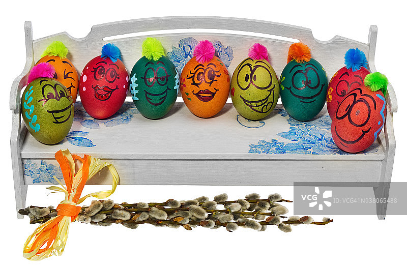 木制长凳上放着画着笑脸的复活节彩蛋。用有趣的彩色发型装饰鸡蛋。图片素材