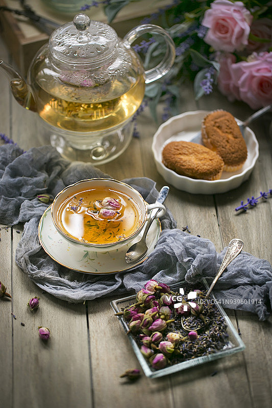 粉红色的玫瑰花茶在装饰杯在木制的桌面上。图片素材