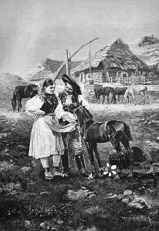 一对年轻农民喂他们的小马驹的村庄场景_ 1895图片素材