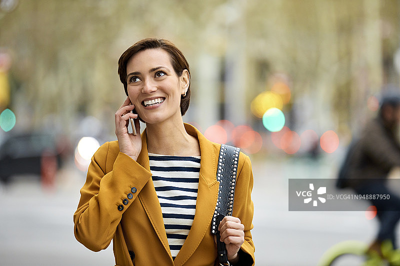 女人微笑着使用手机在城市图片素材