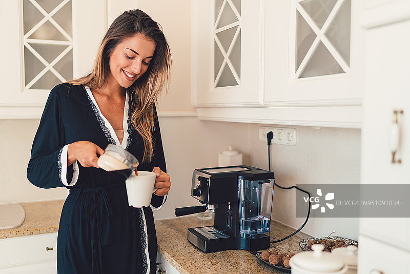微笑的女人在家里准备早上的咖啡图片素材