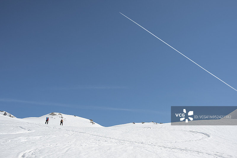 徒步旅行者在白雪覆盖的山谷中行走图片素材