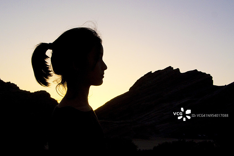女孩马尾辫剪影在瓦斯奎兹岩石在日落图片素材