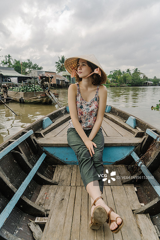 妇女乘船穿过湄公河三角洲和水上市场图片素材