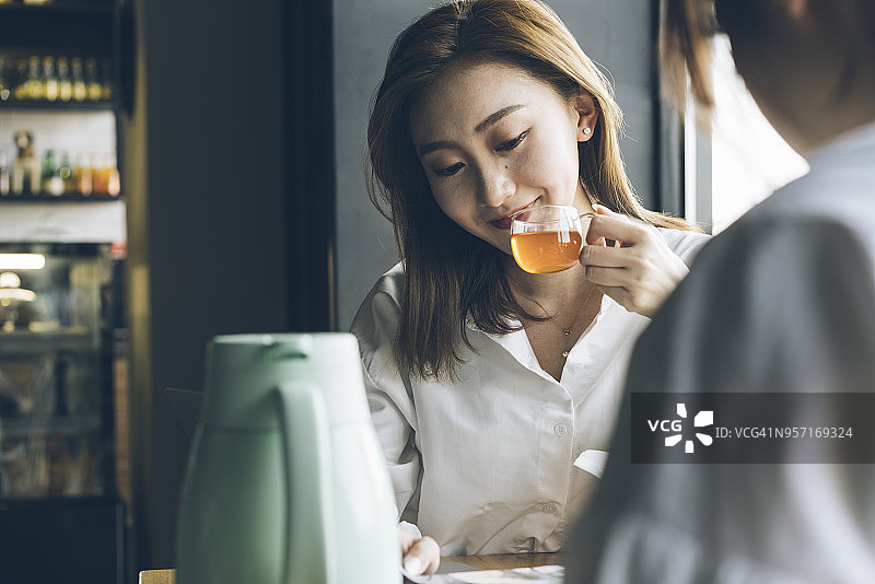 优雅的亚洲女人享受水果茶与朋友在咖啡馆图片素材