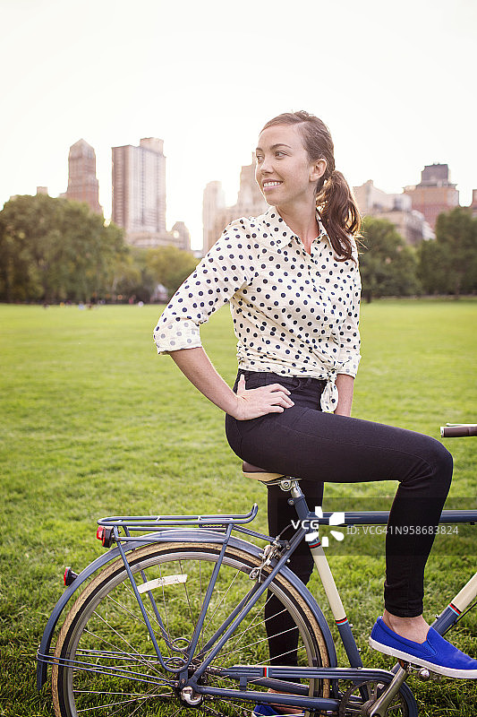 站在中央公园骑着自行车的女人看向别处图片素材
