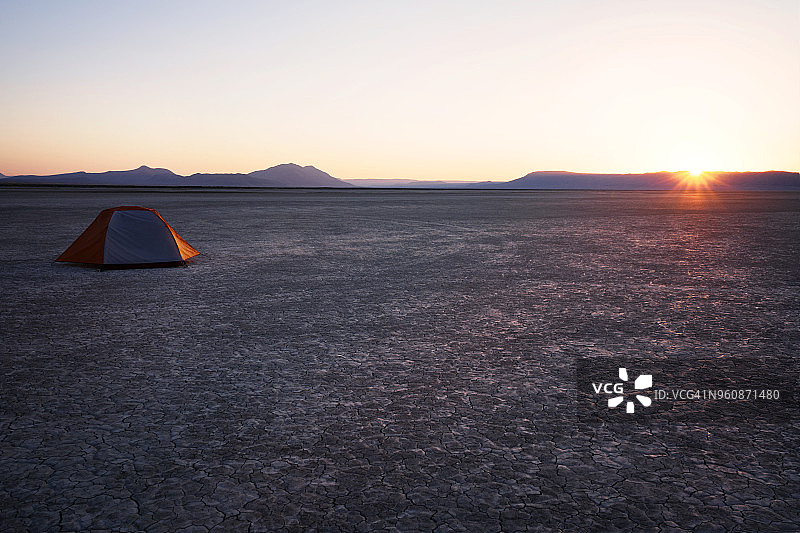 在阿尔沃德沙漠日落时，帐篷在干燥的田野上，背靠山脉和天空图片素材