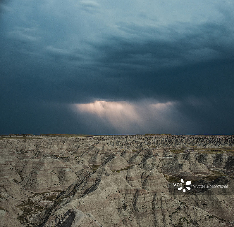 高角度的岩石在Badlands国家公园对抗暴风雨的云层的景观图片素材