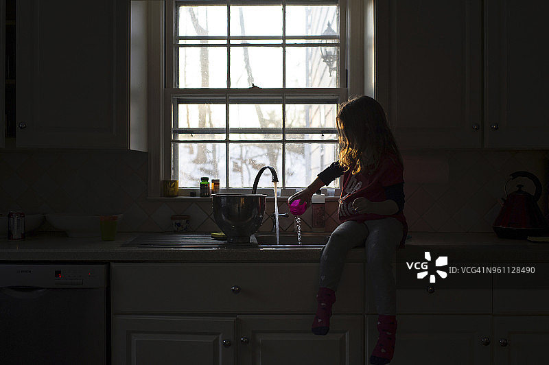 坐在厨房水槽边玩水的女孩图片素材