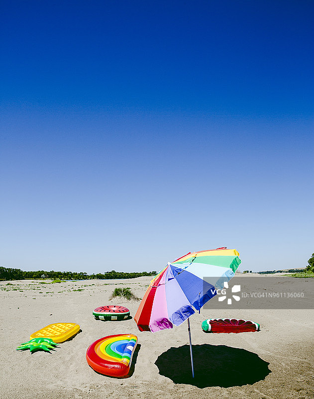 在晴朗的日子里，在海滩上使用阳伞和充气木筏图片素材