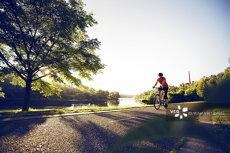 在清澈的天空下，男自行车手在湖边的道路上图片素材