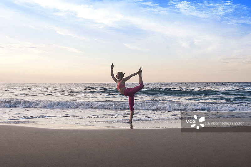 日落时分，女子在海滩上对着天空表演国王舞者的姿势图片素材