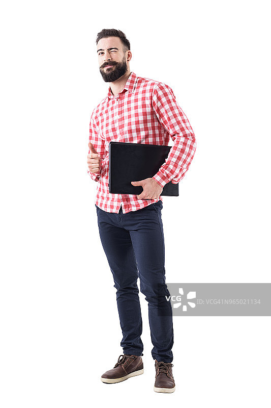 满脸胡须的商人心满意足地眨着眼睛，手臂下夹着笔记本电脑，竖起大拇指图片素材