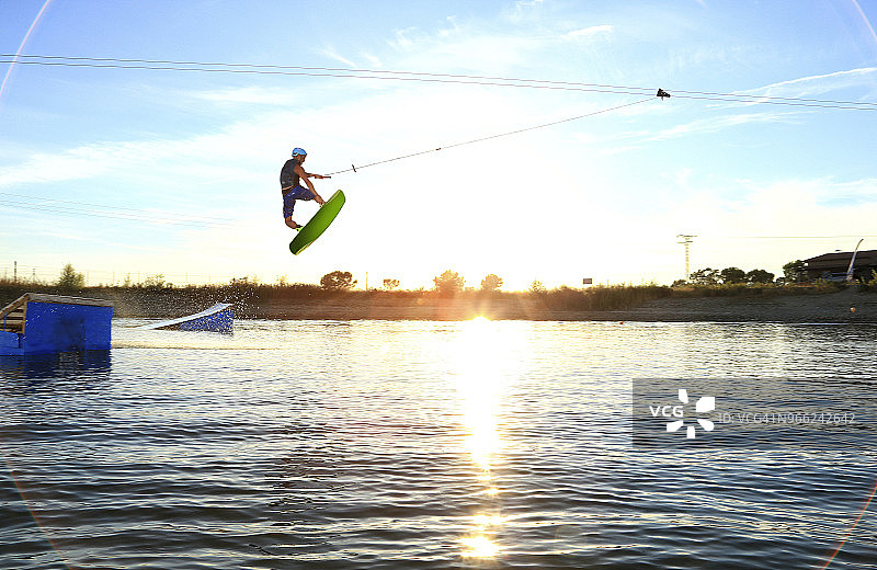日落时分，人在湖上风筝滑板图片素材