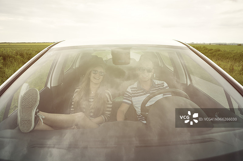 透过挡风玻璃可以看到坐在汽车里的一对快乐的夫妇图片素材