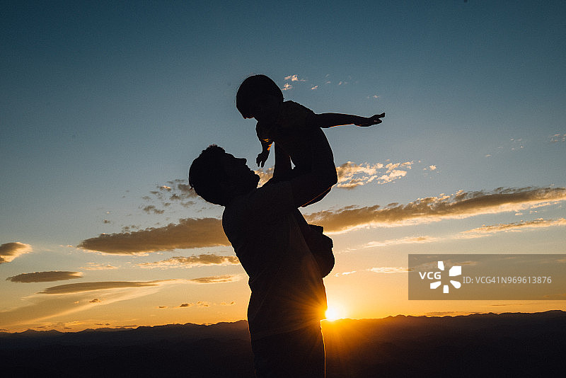 夕阳西下，父亲抱着儿子高高在上图片素材