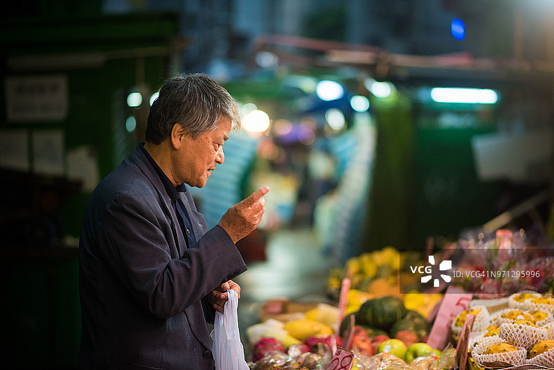 年长亚洲男子在当地市场购物图片素材