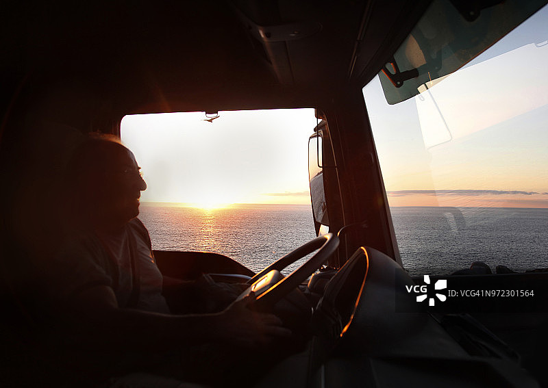 卡车司机的剪影，背景是夕阳和大海图片素材