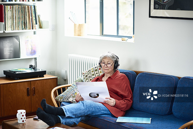 老妇人坐在沙发上戴着耳机听音乐图片素材