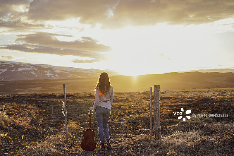 冰岛，日落时分，年轻女子拿着吉他图片素材