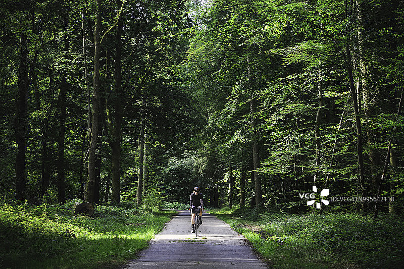 一位女自行车手骑着自行车走出法国的伊威森林图片素材