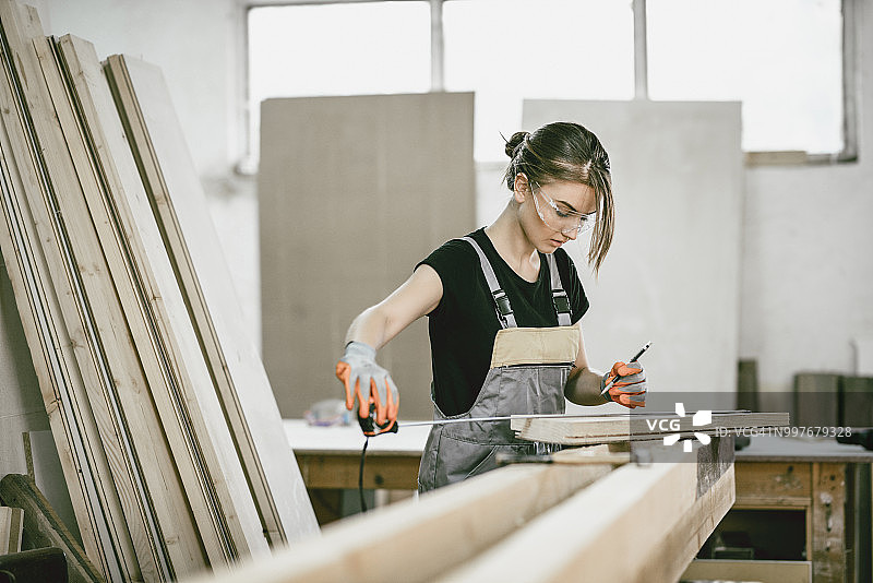 女木匠学徒测量木板的长度和宽度图片素材