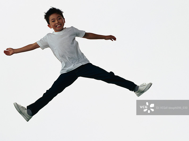 年轻的亚洲男孩穿着牛仔裤和t恤，跳在半空中图片素材