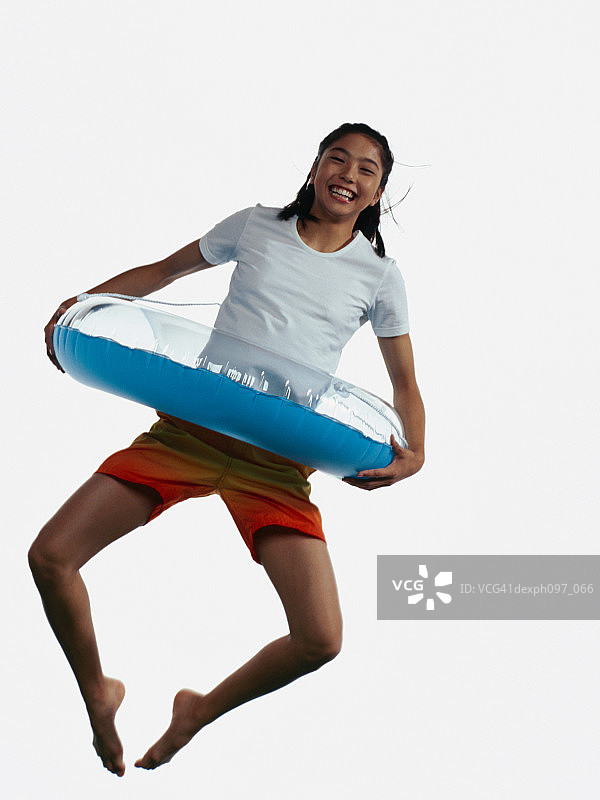 年轻的亚洲女孩带着充气环，在半空中跳图片素材
