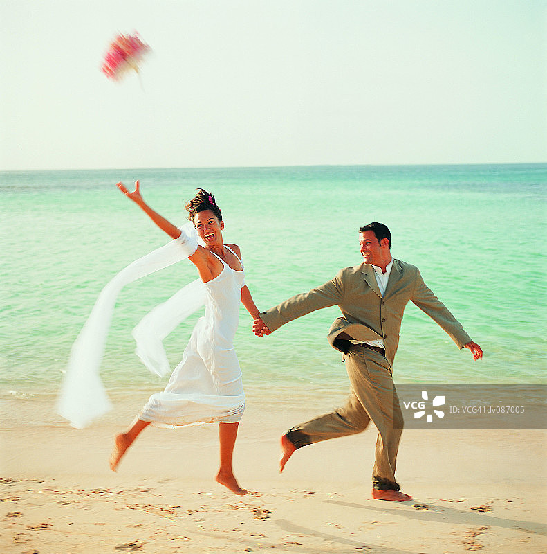 一对新婚夫妇在海滩上跑步图片素材