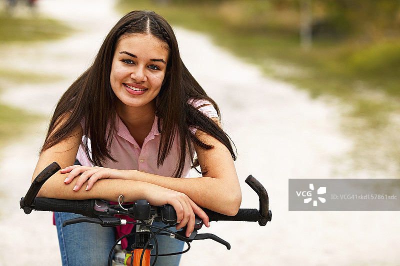 一个十几岁的女孩(16-18)坐在她的自行车上的特写肖像图片素材