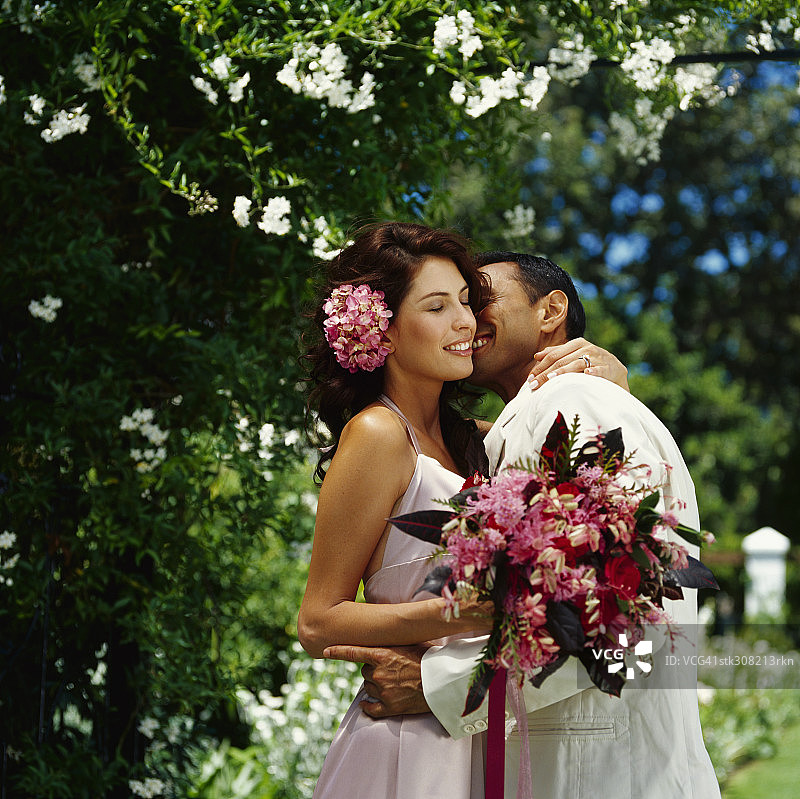 一个新郎亲吻他的新娘在草坪上的侧影图片素材