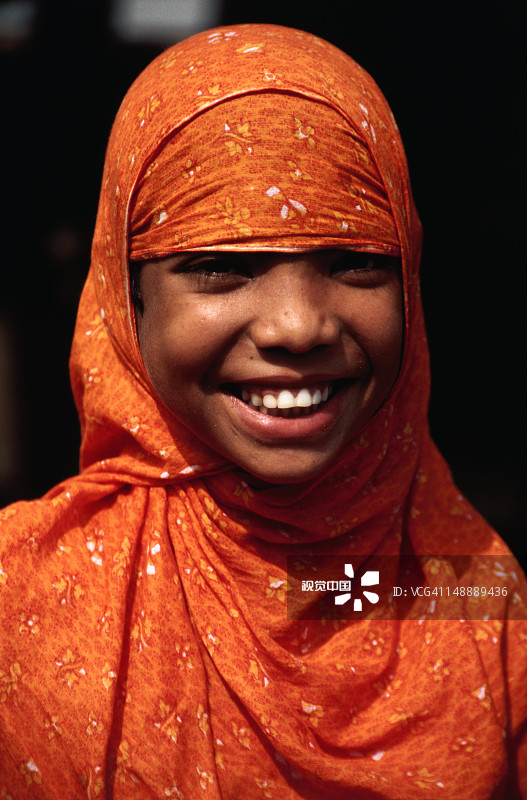 快乐女孩的肖像在明亮的穆斯林服装。图片素材