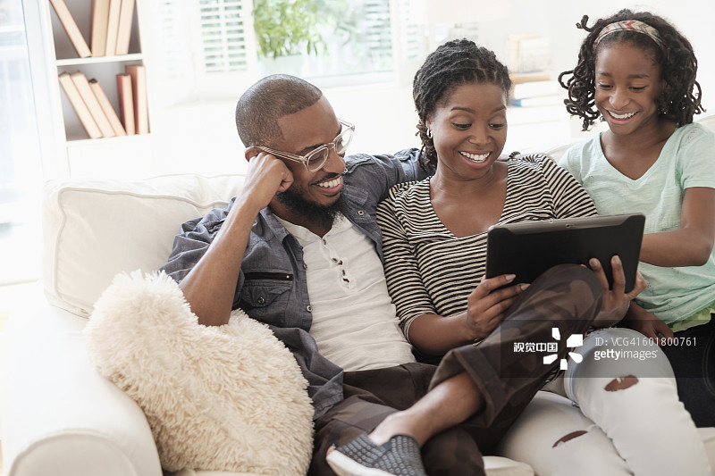 黑人家庭在沙发上使用数码平板电脑图片素材