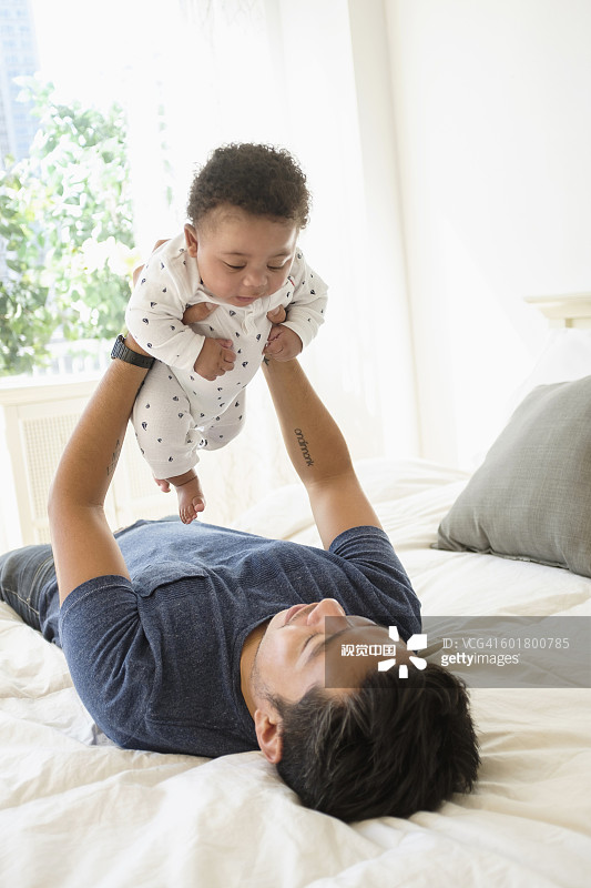 父亲抱着婴儿躺在床上图片素材