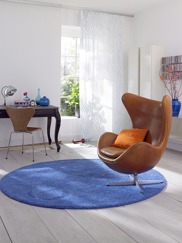 客厅里有棕色的扶手椅和蓝色小地毯上的书桌图片下载