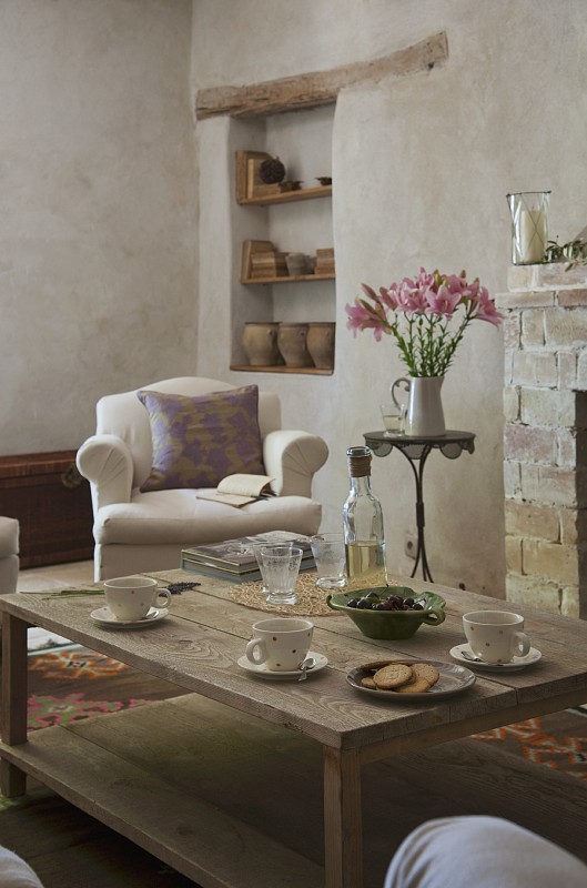 壁炉前的木制咖啡桌;乡村别墅扶手椅和陶瓷架子在壁龛的背景图片下载