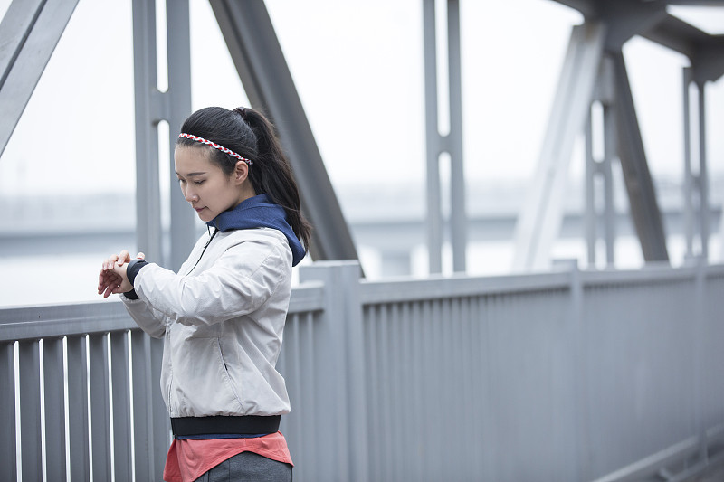 青年女子在跨海大桥上查看智能手表图片素材