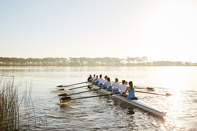 女子赛艇队在阳光明媚的湖面上划桨图片下载