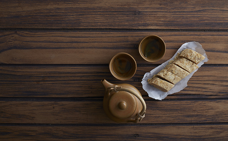 木桌上的糖棒、花生、中国甜点和热茶图片素材