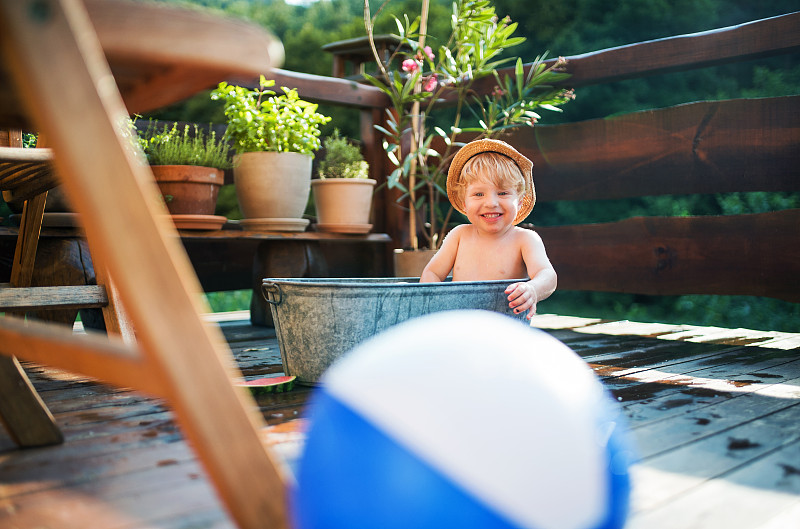 夏天，小男孩带着球在室外花园里洗澡，在水中嬉戏。图片素材