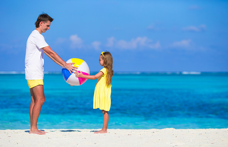 快乐的爸爸和女儿在沙滩上玩球玩得开心图片素材