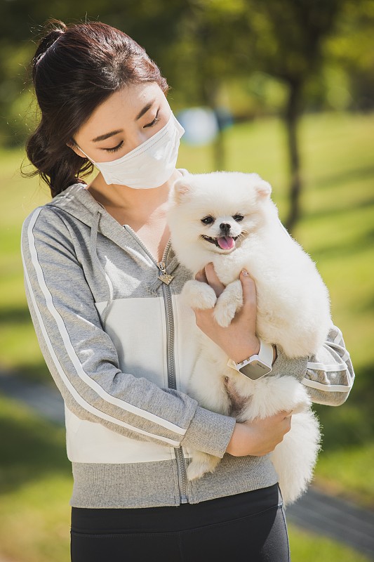 戴着防尘面具，抱着一只狗的女人图片下载