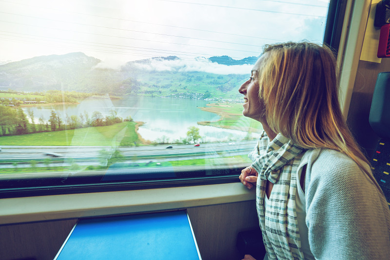 在瑞士乘火车旅行的年轻女子透过窗户看图片下载